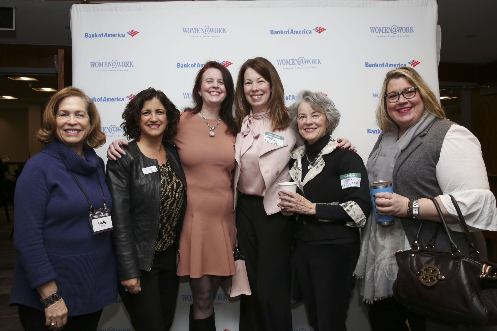 Photo of a group of smiling women in front of the logo'd step and repeat. This photo was taken while attending the Women at Work (Women@work) #networking event in February at the Hearst Times Union building located off of Wolf Road in Albany NY.